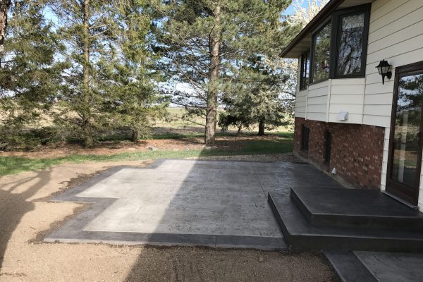 Formed concrete steps on a raised patio with a dark border finish