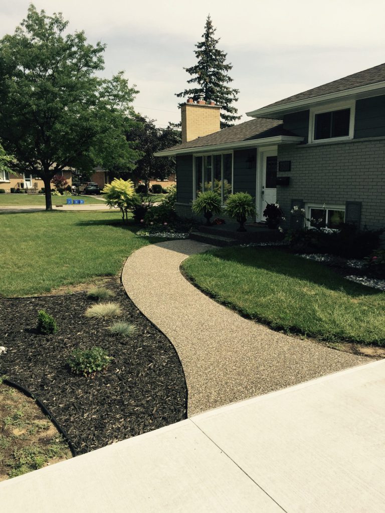 Exposed aggregate concrete walkway through a front garden