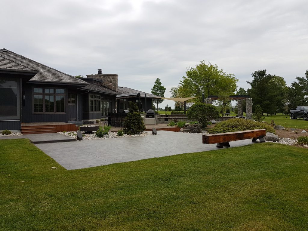 Large stamped concrete patio with pergola and fire pit in Thamesford