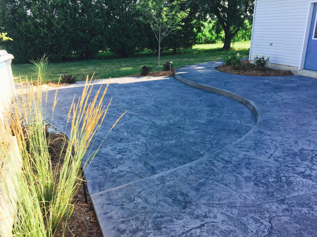 Decorative stamped concrete patio with ornamental grasses