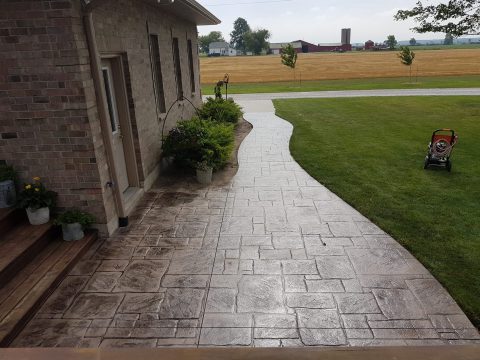 Curved stamped concrete walkway beside a home