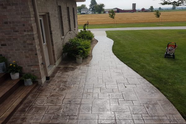 Curved stamped concrete walkway beside a home