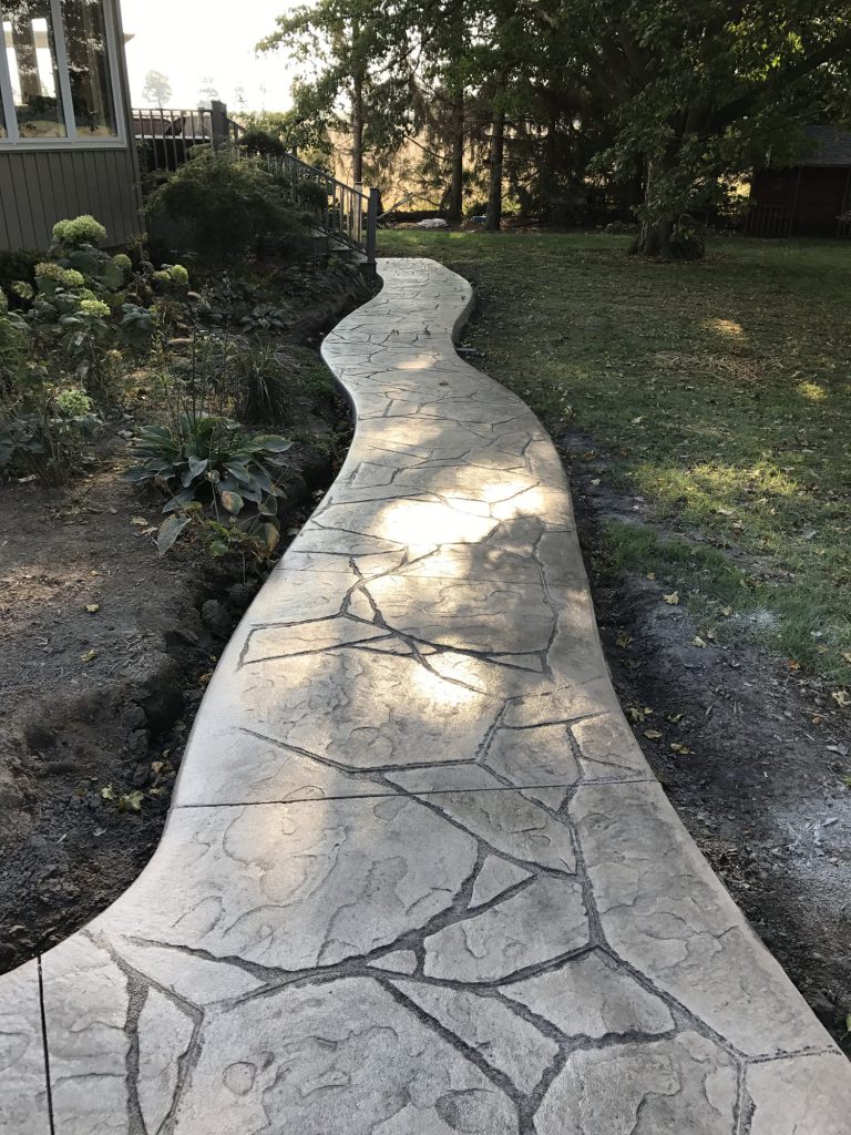 Stamped concrete walkway in a flagstone pattern through a garden